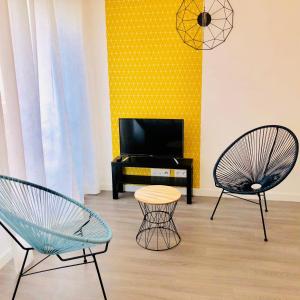 维勒班特BtoBed - 巴黎北维勒班特公寓的客厅配有两把椅子和电视
