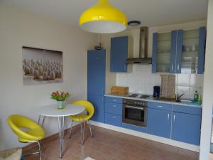 博恩Boddenpieper的厨房配有蓝色橱柜和一张带黄色椅子的桌子