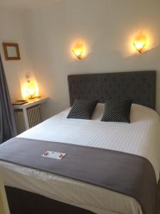 Buzançais国际之家隐居之处酒店的卧室配有一张大床,墙上有两盏灯