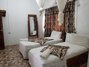 KenemaPaloma Guest House的带两张床和镜子的客房