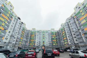 苏梅VIP Apartments Faraon on Kharkovskaya 1 floor的停车场,有汽车停在高楼前