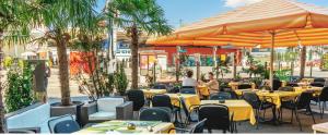 弗劳恩费尔德Hotel Blumenstein Self-Check In的餐厅设有桌子、遮阳伞和棕榈树。