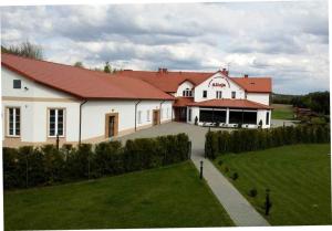 KsiężpolCentrum Turystyki Wiejskiej Alicja的一座白色的大建筑,前面有一个绿色的草坪