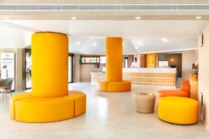 阿德耶阿德赫海岸塔哥洛家庭欢乐酒店的大堂设有黄色柱子和橙色椅子