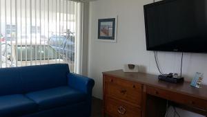 怀尔德伍德Tide Winds Motel的客厅配有蓝色的沙发和平面电视。