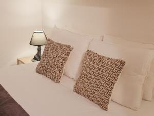 卡尔卡维洛斯Like-home Sea View Apt的一张带白色枕头的床和一张桌子上的台灯