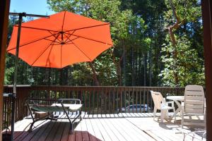 GabriolaGabriola Central B&B的庭院配有桌椅和橙色遮阳伞。