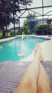 海恩斯城Maya's Villa的躺在游泳池前的女人,喝一杯葡萄酒
