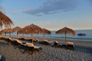 博尔迪盖拉Hotel Villa MIKI的海滩上的一组椅子和草伞