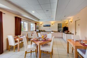 拉菲克拉Vacancéole - Résidence Les Balcons d'Aix的用餐室配有木桌和白色椅子