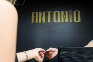 乌日霍罗德Hotel Antonio的一个女人在天线标志前拿着手机