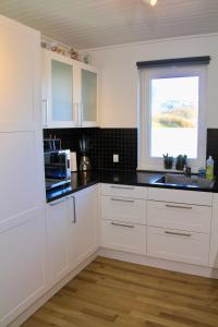 托尔斯港Nordic Inn Thorshavn的厨房配有白色橱柜和窗户。
