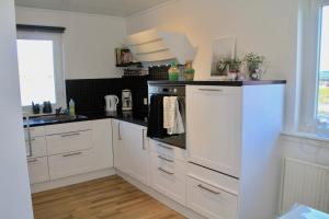 托尔斯港Nordic Inn Thorshavn的厨房配有白色橱柜和炉灶烤箱。