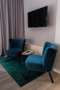 科隆rugs HOTEL Köln的配有电视的房间,设有两把蓝色椅子