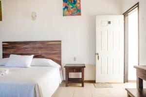 埃斯孔迪多港齐卡特拉简易别墅酒店的卧室配有白色的床和木制床头板