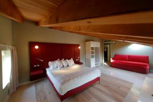 拉齐塞Le Greghe Suites的一间卧室配有一张大床和一张红色的沙发