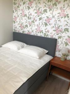 瓦尔贝里Annelund的一张铺有白色床单的床和墙上的粉红色花卉