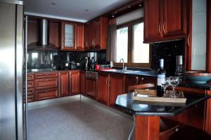 斯基亚索斯镇Poseidon villa m ammos的厨房配有木制橱柜和黑色台面