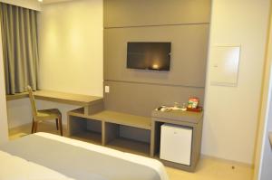 Marechal Cândido RondonHospedare Hotel的酒店客房设有一张床、一张书桌和一台电视机。