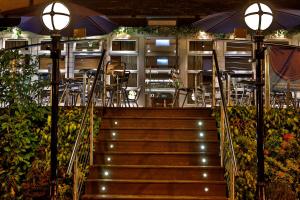 马瑟韦尔Best Western Motherwell Centre Moorings Hotel的楼梯通往带桌子和遮阳伞的餐厅