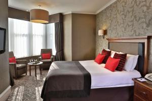 马瑟韦尔Best Western Motherwell Centre Moorings Hotel的酒店客房配有一张带红色枕头的大床