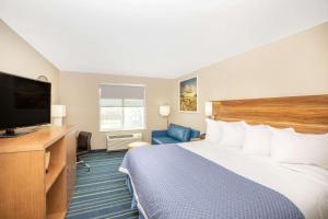 科尔尼Days Inn & Suites by Wyndham Kearney NE的配有一张床和一台平面电视的酒店客房