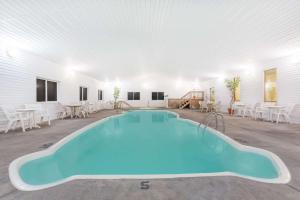 德里格斯Super 8 by Wyndham Driggs的白色客房的大型游泳池,配有桌椅