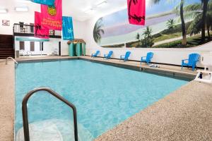HuronSuper 8 by Wyndham Huron的一座大型游泳池,位于酒店带蓝色椅子的房间内