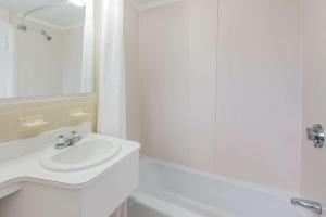 西雅茅斯西茅斯海恩尼斯/科德角速8汽车旅馆的白色的浴室设有水槽和浴缸。