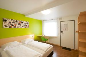 索斯特索斯特城市汽车旅馆的卧室配有白色的床和绿色的墙壁