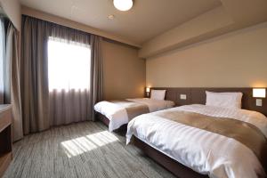 高松多美迎高松中央公园前酒店的酒店客房设有两张床和窗户。