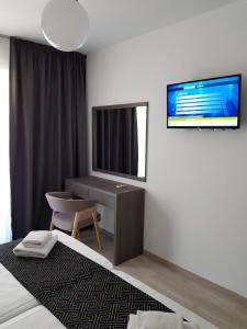 拉纳卡Les Palmiers Petrou Apartments的一间卧室配有一张床、一张书桌和一台电视