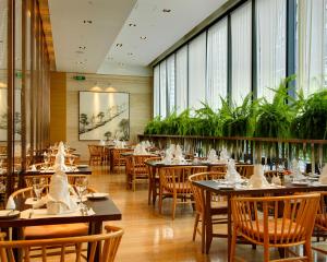 北京北京中奥马哥孛罗大酒店的用餐室配有桌椅和植物