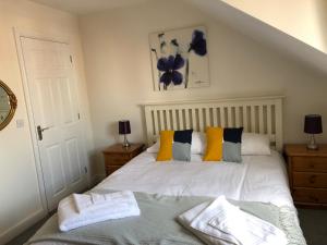 奥克姆Jubilee House的一间卧室配有白色的床和黄色及蓝色枕头