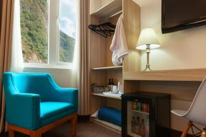 马丘比丘Inti Punku Machupicchu Hotel & Suites的一间设有蓝色椅子和窗户的客房
