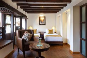 帕坦Hotel Patan House的配有床、椅子和桌子的酒店客房