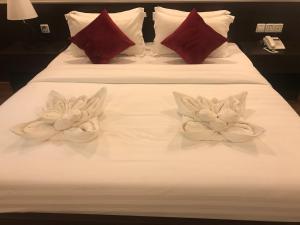 金边Apple Hotel Two - Near Phnom Penh Airport的白色床上的两朵白色鲜花和红色枕头