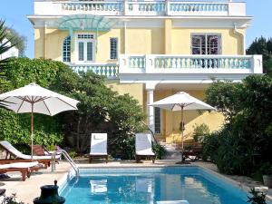 尼斯Villa Dracoena的房屋前的带椅子和遮阳伞的游泳池
