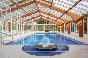 厄维召特Summer Lodge Country House Hotel的一个带玻璃天花板的室内游泳池和一个游泳池