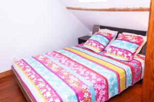 SalencyMaison de village Salency的一间卧室配有一张带色彩缤纷的床单和枕头的床。