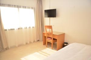 达赫拉Hotel El Bachir的一间卧室配有一张桌子和一张椅子,位于床边