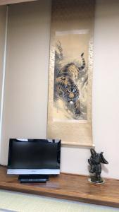 金泽金马醋民宿旅馆的架子上的电视,上面有老虎的照片
