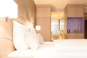 慕尼黑慕尼黑雷莱克萨酒店的卧室配有白色的床铺和白色的枕头