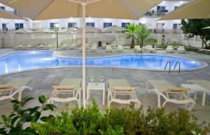 萨洛萨洛海滩皮埃尔假日酒店 的酒店前方设有1个带桌子和遮阳伞的游泳池。