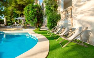 坎皮卡福特埃斯巴乌洛佩提特酒店的一组躺椅,坐在游泳池旁