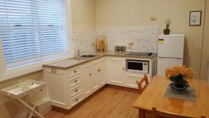 EvandaleArendon Cottage的厨房配有白色橱柜、桌子和冰箱。