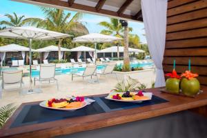 维约堡Serenity at Coconut Bay - All Inclusive的两个盘水果放在泳池旁的桌子上
