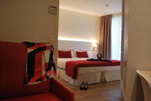 潘普洛纳Hotel Pompaelo Plaza del Ayuntamiento & Spa的酒店客房,配有一张床和一张红色椅子