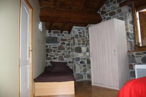 Axiatla forge d'andribet的一间卧室设有石墙、一张床和一个橱柜