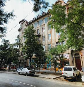 敖德萨诗人艺术酒店的两辆汽车停在街道上一座建筑物前面